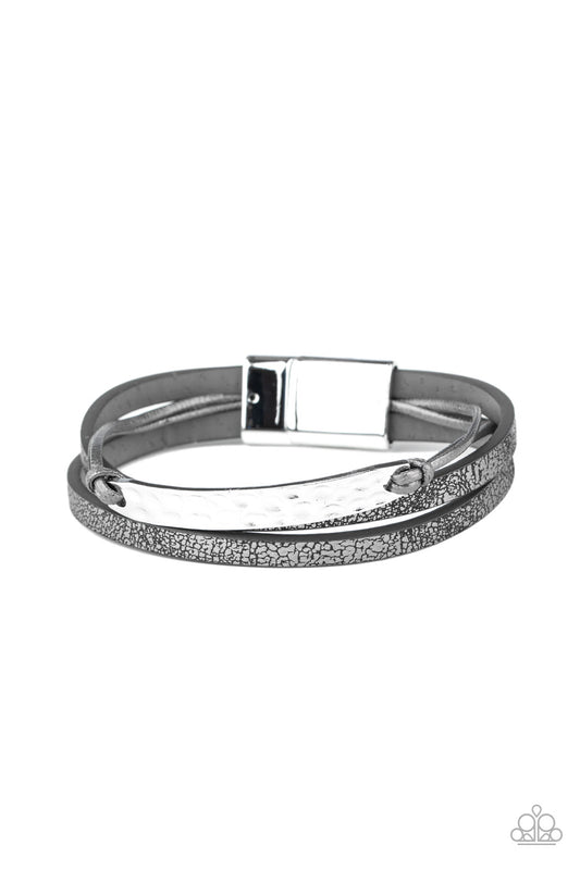 Shiny gray cords and pieces of metallic flecked gray leather layer across the wrist.