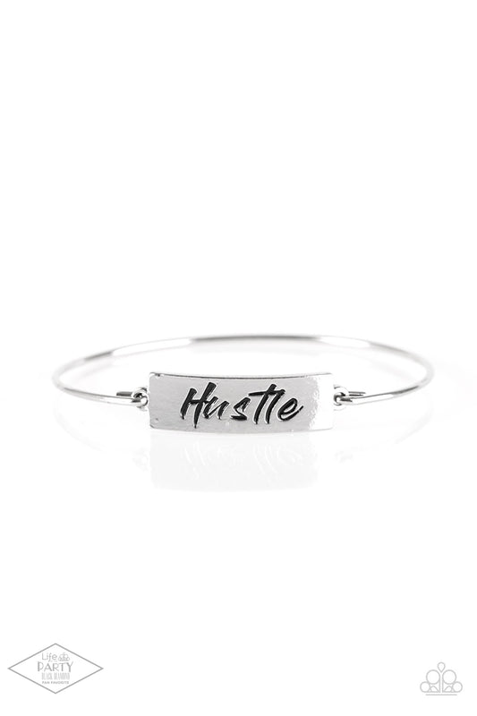 Engraved with the inspiring word "Hustle", a shimmery silver plate attaches to a skinny silver bar, creating a dainty bangle.