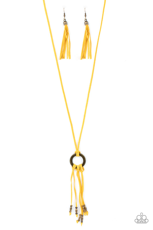 Infused with dainty brass beads, strands of yellow suede knot at the bottom of an antiqued brass ring, creating a colorfully rustic tassel at the bottom of a lengthened strand of yellow suede. Features an adjustable sliding bead closure.