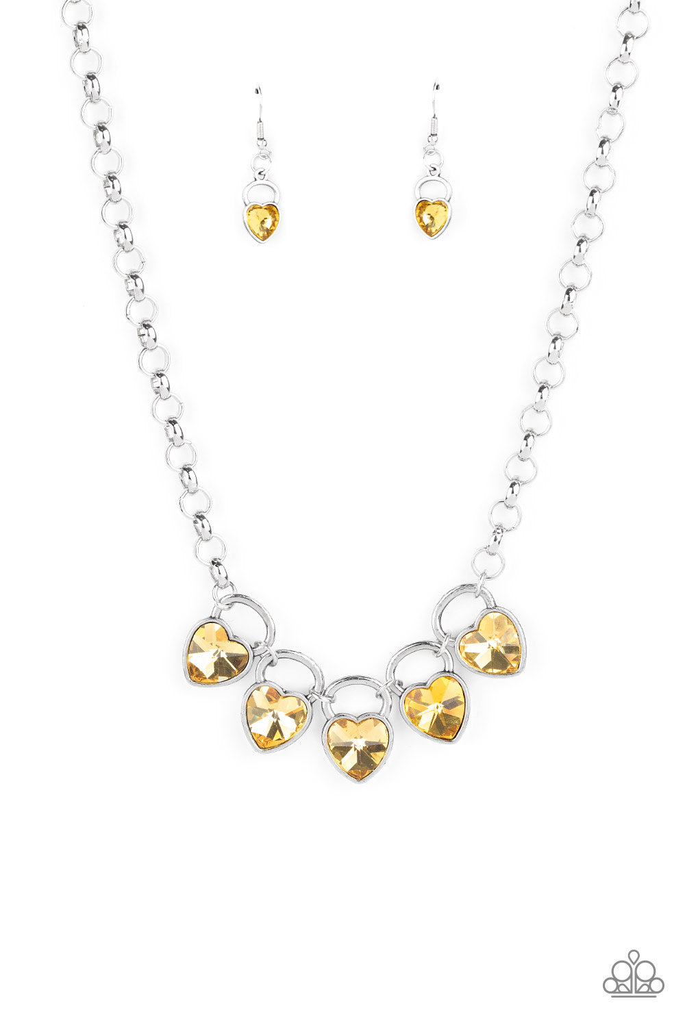 Dotted with glittery yellow heart-shape gems, shimmery silver locket-like frames link together at the bottom of an exaggerated silver chain, creating a sparkling statement piece below the collar.